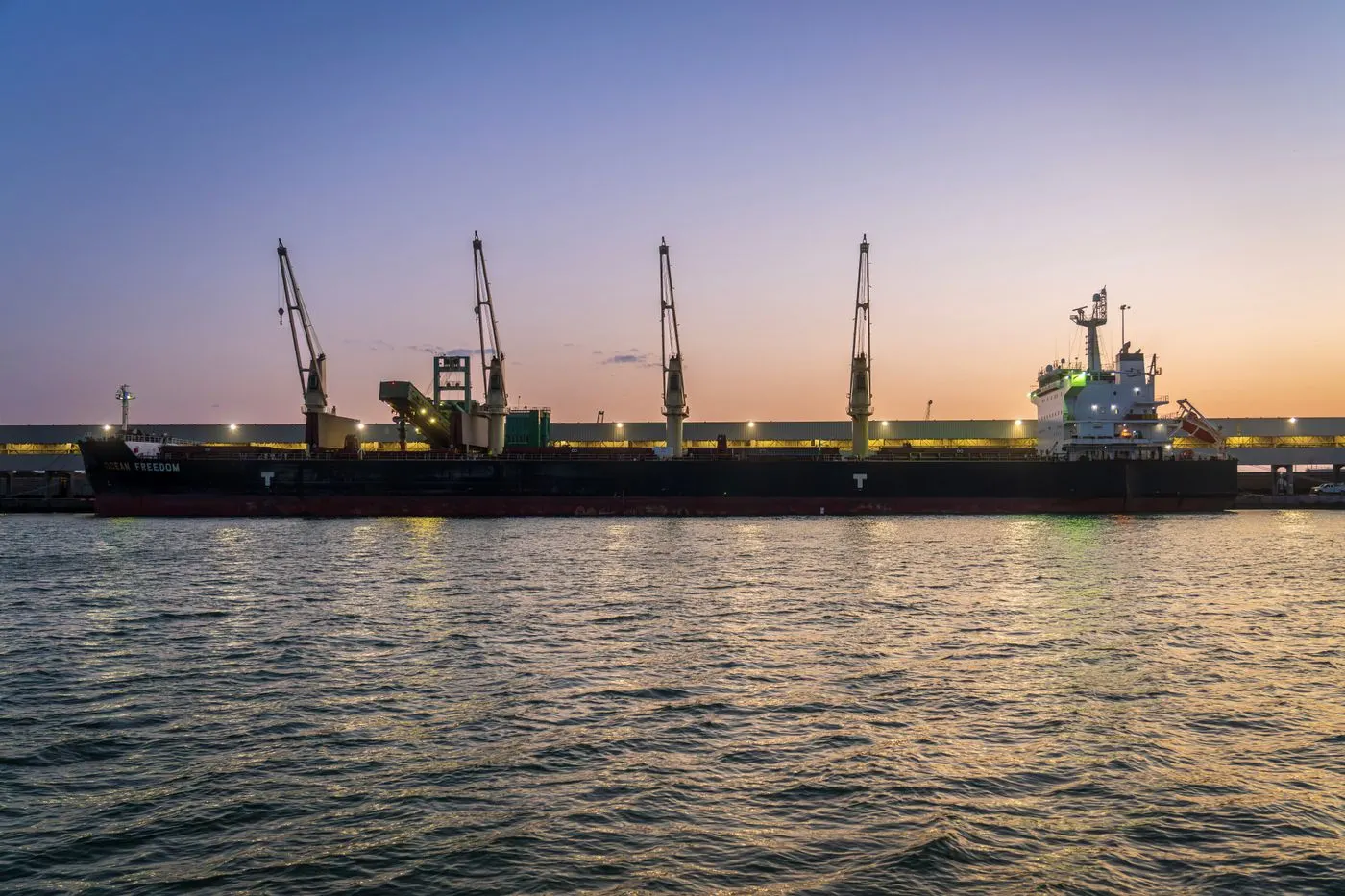 Geared bulk carrier alongside a quay at dusk