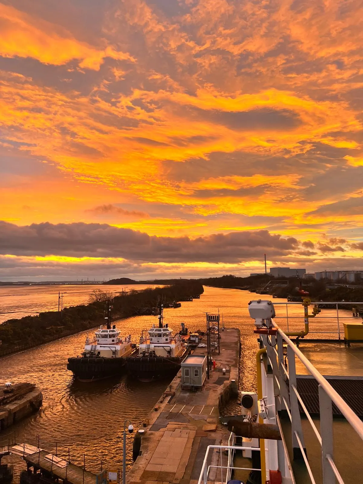 Sunset over a port channel with tugboats moored alongside